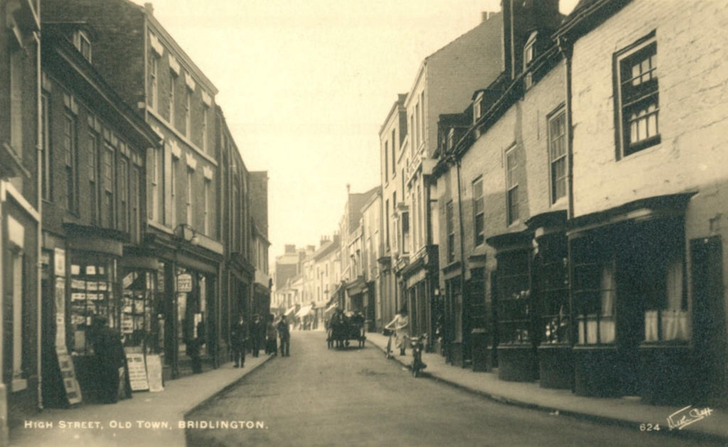 A vintage black and white photograph print depicting High Street in Old Town, Bridlington, showing a narrow street lined with old brick and timber buildings, with pedestrians and horse-drawn carriages in the distance.